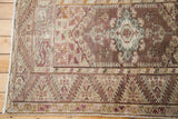 Vintage Anatolian rug with lilac, brown, and turquoise geometric medallion detail.