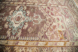 Vintage Anatolian rug showing cream border with geometric patterns in lilac, brown, and pale blue.