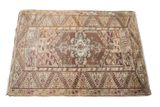 Vintage Anatolian rug with central geometric medallion in lilac, brown, and earth tones.