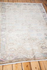 Light field and soft floral motifs on a vintage Oushak rug with geometric border.