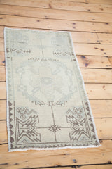 Corner of vintage Oushak rug, hand-knotted pile with blanched background, taupe and pale blue geometric patterns.