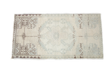 Small blanched vintage Oushak Turkish rug with faded geometric patterns.