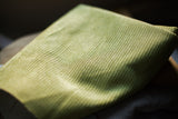 Soft muted green corduroy fabric showing its fine ribbed texture for pillow backing.