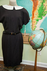 Vintage 80s black dress at the waist, featuring a black belt with a gold-tone buckle.
