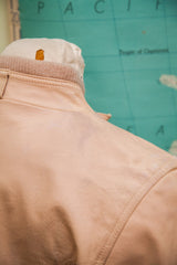 Vintage light pink leather jacket shoulder, subtle markings and ribbed collar.