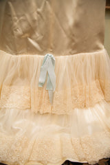Vintage bridal slip's intricate peach lace tiers with light blue satin ribbon accent.