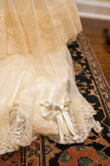 Vintage ivory slip with lace trim, elegant satin bow, and delicate blue flowers.