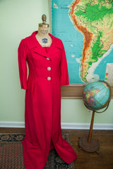 Front of a vintage 60s hot pink coat showing its notched lapels and ornate rhinestone buttons.