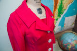 Angled view of the hot pink vintage coat's wide collar and rhinestone buttons.