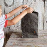 Hands opening the moss green waxed canvas Marlowe Lunch Bag.
