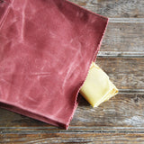 Angled view of the Radish waxed canvas lunch bag, showing its texture and yellow item.