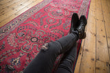 Angled view of a vintage Meshed runner's raspberry red field with Sarouk floral sprays.