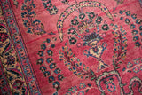 Intricate cloud-band arch over a floral bouquet on a cochineal red hand-knotted runner.