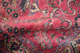 Close-up on the even wool pile, showing intricate floral and cloud-band motifs in raspberry red.