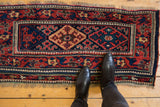 Antique Kurdish saddlebag runner with intricate pawn motif borders and medallions, shown for scale.