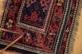 Corner of an antique Kurdish rug showing the intricate pawn motif and meandering floral borders.