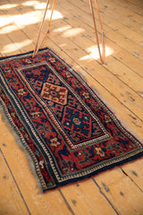 Antique Kurdish runner with geometric medallions and rich indigo and red tones styled in a room.