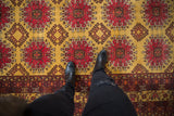Top-down view showing the plush texture and saffron yellow field of a vintage Daulatabad carpet.