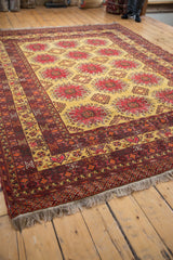 A vintage Daulatabad carpet's saffron field and raspberry red pawn motifs viewed from a low angle.