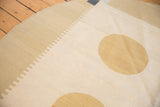 Fine weave of an abstract modern kilim showing a rounded dusty gold motif and rectilinear ivory accents.