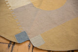 Curved edge of contemporary kilim, showing fine weave with abstract beige, gold, and navy pattern.