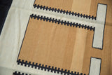 Geometric design of sand and ivory with charcoal sawtooth borders on a contemporary Kilim.