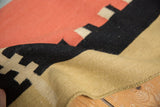 Folded contemporary Kilim rug, revealing handwoven flatweave in black, cinnabar, and sand.
