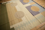 Dark olive green, sand, and pale violet purple blocks with abstract circles and running zipper elements.