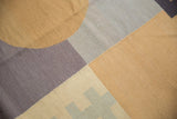 Textured flatweave with abstract blocks, curved line, and zipper elements in beige, silver, and pale violet.