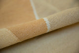 Rolled contemporary Kilim carpet showing its handwoven texture in pale copper and ivory.