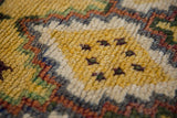 Close-up of the soft, full pile of a vintage Moroccan rug with saffron and ivory wool knots.
