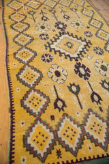 Soft saffron yellow pile of a vintage Moroccan rug with diamond medallions and floral designs.