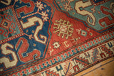 Pawn motif and serrated leaf borders on a Kazak rug in brick red, sapphire blue, and oxidized green.