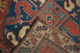 Folded corner of an antique Kazak rug showing the geometric pawn motif border and hand-knotted pile.