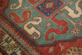 Bold cloud-band dragon motif in brick red and ivory on an oxidized copper-green field.
