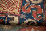 Close-up of a late 19th-century Kazak rug's weave, showing bold dragon motifs in sapphire blue and brick red.