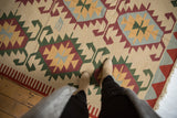 Serrated geometric medallions in ivory, wine red, powder blue, and green on a vintage Kilim.