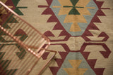 Serrated geometric rams horn motifs on a vintage Turkish Kilim in ivory, wine red, and powder blue.
