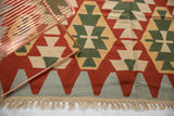Vintage Turkish Kilim rug secured end with ivory fringe and serrated geometric pattern in rust, green, blue.