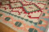 Angled view of vintage Turkish Kilim border with ivory, red, green, peach, blue patterns.
