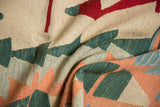 Textured hand woven Turkish Kilim with serrated geometric shapes in ivory, red, green, and peach tones.