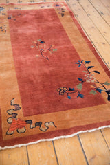 Corner detail of an Art Deco rug with potted floral vases and scrolling cloudband motifs.