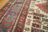 Angled view of the low pile and serrated border in sky blue and red on a vintage Karaja rug.
