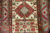 Geometric bird figures and a serrated red medallion on the ivory ground of a vintage Karaja rug.