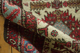Hand-knotted pile of a folded Karaja runner with geometric floral details in red, blue, and ivory.