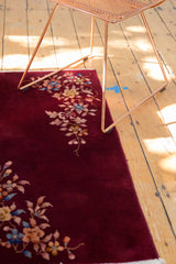 Colorful corner floral sprays on the deep burgundy pile of a vintage Art Deco rug.
