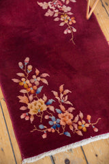 A corner floral spray with sky blue and saffron on the vintage rug's burgundy pile.