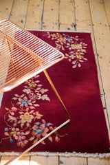 Styled view of a vintage Nichols Art Deco rug showing its rich burgundy color and floral corner sprays.