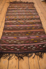 Dark brown fringe and geometric serpent patterns of the Jijim rug.