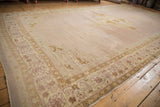 An antique Agra carpet's open, abrashed mauve field and intricate pale gold and lavender borders.
